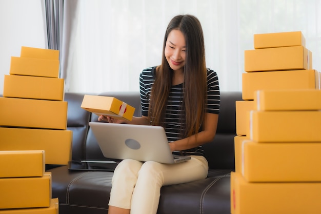 Portrait of beautiful young asian woman with cardboard parcel boxes and laptop